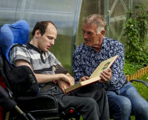 Foto on horisontaalse ristküliku kujuline. Isa Valdeko istub aias toolil. Temast vasakul on täiskasvanud poeg Tanel invakärus. Valdekol on lühikesed hallid juuksed. Tal on seljas sinisekirju päevasärk, jalas teksad. Poeg Tanelil on lühikesed pruunid juuksed ja kõrge laup. Tal on seljas hallitriibuline särk ja tumehallid püksid. Isa hoiab parempoolse käega avatud raamatut Taneli põlvedel. Vasakpoolne käsi on asetatud raamatulehele. Naeratava isa pilk on suunatud poja näole. Tema silmade ümber on sügavad vaod. Poeg Taneli nägu on pööratud raamatu poole, silmad suletud. Mustal invakärul on sinine katteriie. Isa ja poja selja taga on kasvuhoone, mille servas kasvavad äraõitsenud roosid.